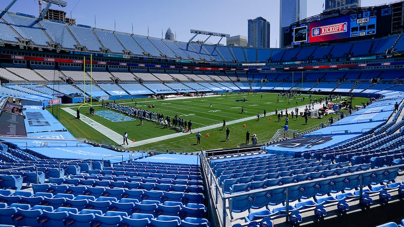 Members of the Carolina Panthers stand during a special presentation in an empty stadium...